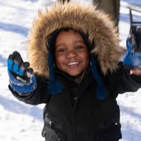Child smiling in the snow during winter outreach